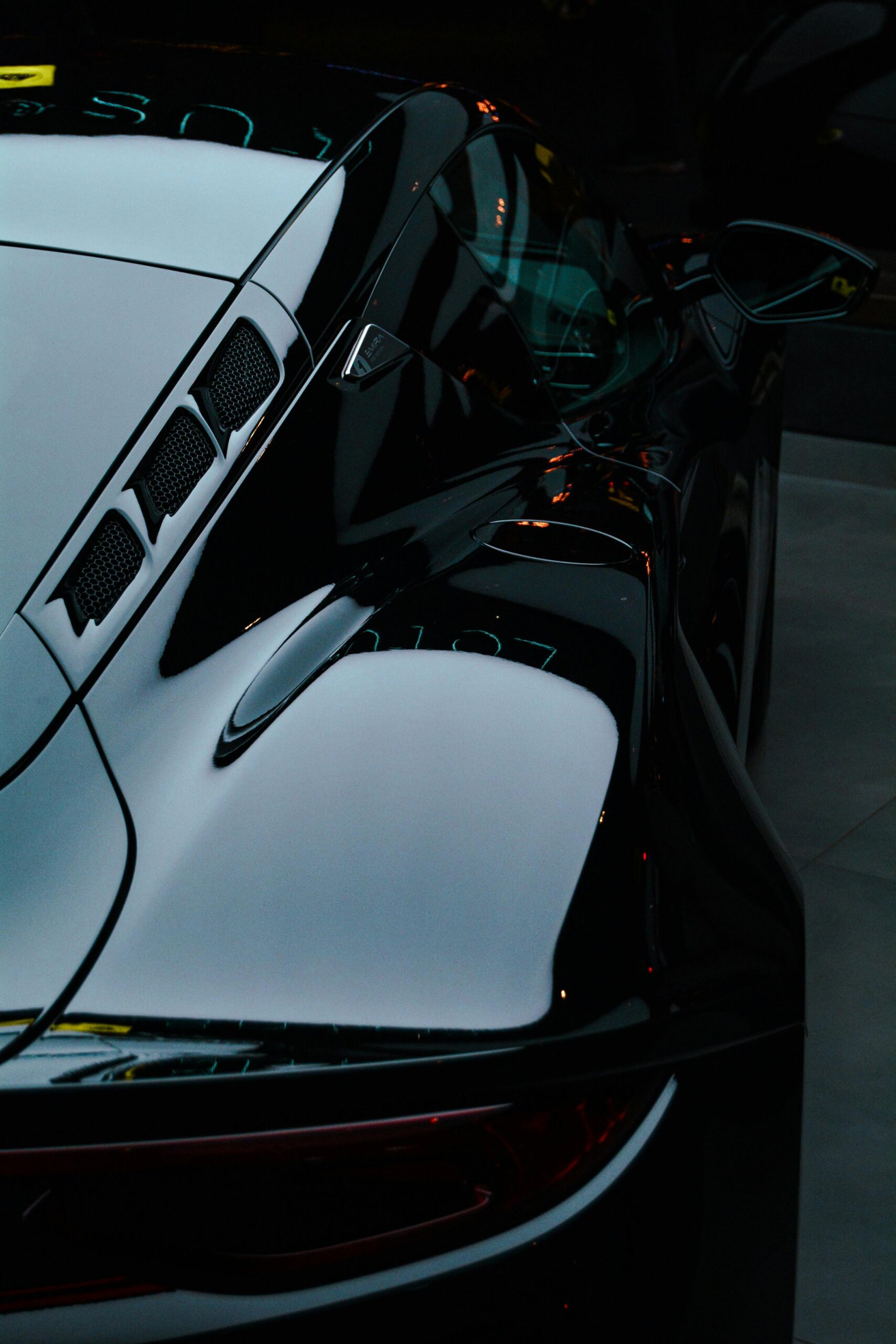 Close-up of a glossy black sports car showcasing aerodynamic design and reflections.